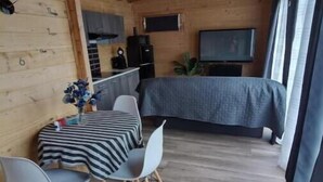 Une chambre confortable de style cabane, comprenant un coin repas, un lit et un téléviseur.
