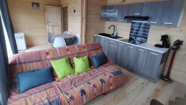 Un intérieur de chalet chaleureux avec un canapé, une table à manger et un coin cuisine.