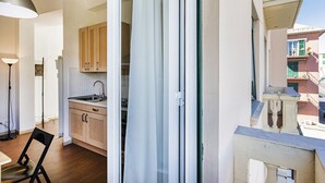 A modern kitchen with wooden cabinets, a sink, and a dining area with a chair. - Casa Camilla al Mare by Wonderful Italy (Genoa)