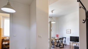A room with a dining area, a TV, and a small table with a candle. - Casa Camilla al Mare by Wonderful Italy (Genoa)