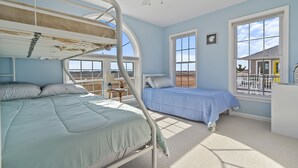 Un dormitorio con literas, ventilador de techo, ventanas amplias y vistas del paisaje.