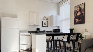 Eine moderne Küche mit weißen Schränken, einem Backofen, einer Mikrowelle und einem Essbereich mit Barhocker.