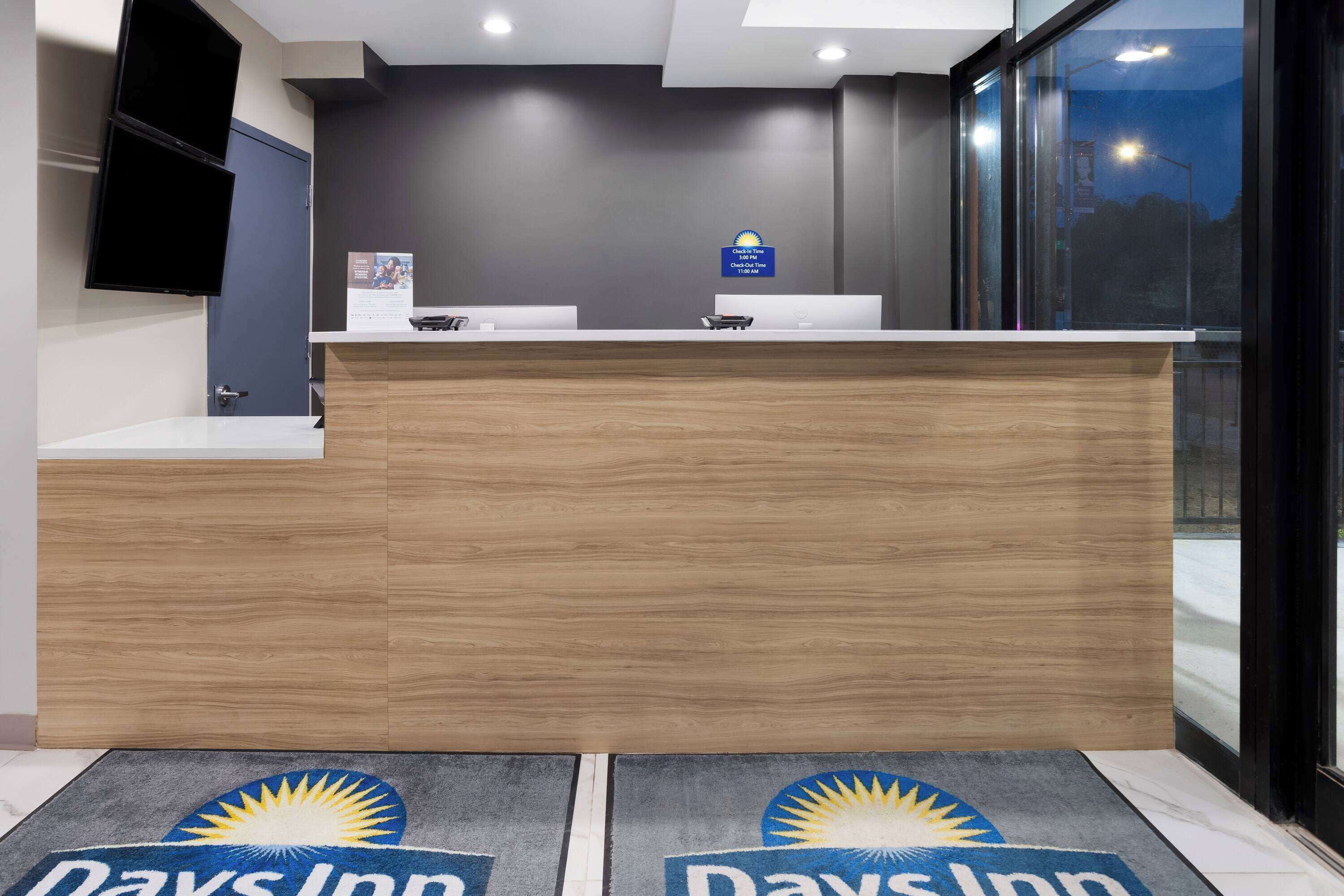En receptionsdisk med en träbeklädd bardisk, en platt-TV som är monterad på väggen och ett stort fönster med utsikt över omgivningen.