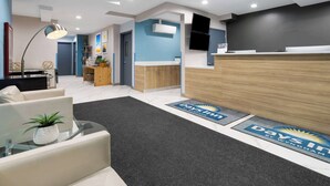 A reception area with a desk, chairs, a plant, and a reception counter. - Days Inn By Wyndham Staten Island (Staten Island)