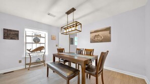 A dining area with a wooden table and chairs, a bench, a hanging light fixture, and a window with a view of the beach. - Walk to bar, shop, and DT (Port Sanilac)