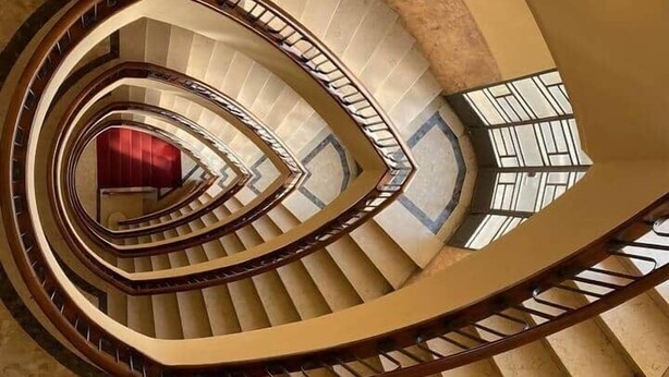 A spiral staircase with a wooden handrail and beige steps, leading to an upper floor. - Urban Jungle apt - Self Check-in, Metro, Train (Torino)