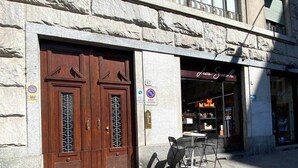A stone building with large wooden double doors and a cafe named "Juice & Coffee" with outdoor seating. - Urban Jungle apt - Self Check-in, Metro, Train (Torino)