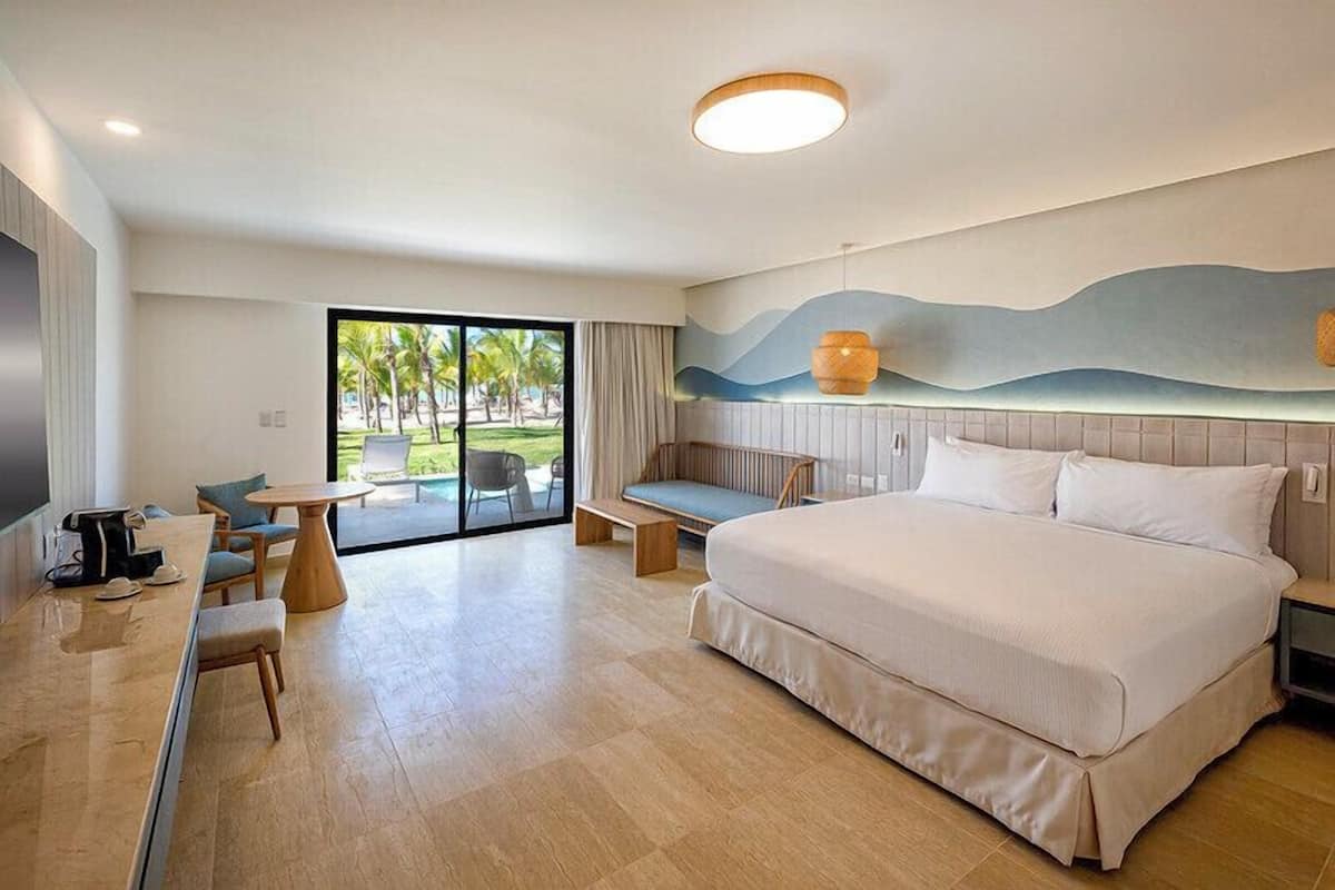Une chambre d’hôtel moderne avec un grand lit, un bureau avec une chaise, une petite table et un banc.