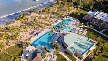 Vista aérea de un resort con varias piscinas, acceso a la playa y palmeras.