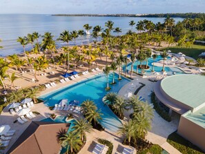 Un resort con una piscina grande, palmeras y vista al océano.