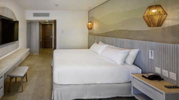 A modern hotel room with a large bed, a bedside table with a phone, a bench, and a TV mounted on the wall.
