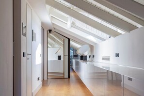 A modern interior with a glass partition, a ceiling with skylights, and a long counter. - Roof Garden Cavour - Design and comfort/Parking (Como)
