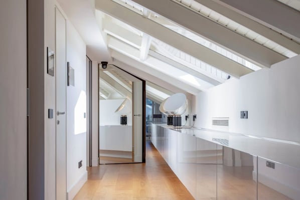 A modern interior with a glass partition, a ceiling with skylights, and a long counter. - Roof Garden Cavour - Design and comfort/Parking (Como)