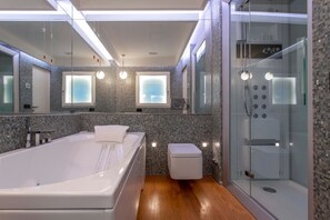 A modern bathroom with a large bathtub, a glass-enclosed shower, and a toilet.