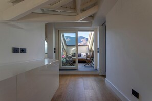Un intérieur moderne avec un plancher en bois et une porte-fenêtre coulissante donnant sur un balcon avec vue sur les montagnes.