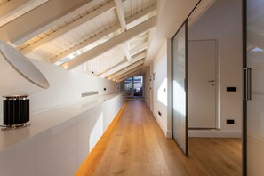A modern interior with a long hallway, wooden flooring, and a sloped ceiling with skylights. - Roof Garden Cavour - Design and comfort/Parking (Como)