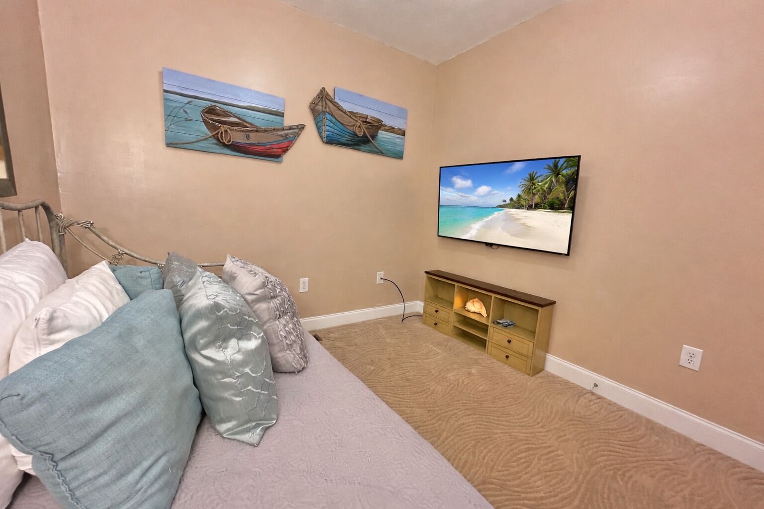 A bedroom with a bed, pillows, a TV, and wall art.