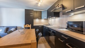 Uma cozinha moderna com mesa de jantar de madeira, eletrodomésticos embutidos e luminária contemporânea.