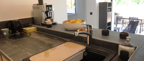 Eine moderne Küche mit einer Kaffeemaschine, einer Obstschale und einem Spülbecken.