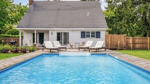 A swimming pool with lounge chairs, a wooden deck, and a house with a grey roof and white walls. - Centrally Located in East Quogue, Perfect for Families, Private Pool, Close... (East Quogue)