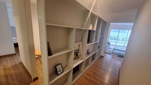 A spacious room with a wooden floor, a large window, and a built-in bookshelf with various decorative items. - Gorgeous 2BDRM with A/C - Miraflores (Miraflores)