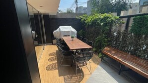 A balcony with a wooden table and chairs, a covered grill, and a bench. - Gorgeous 2BDRM with A/C - Miraflores (Miraflores)