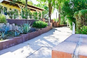 Un sendero bordeado de plantas y una estructura cubierta.