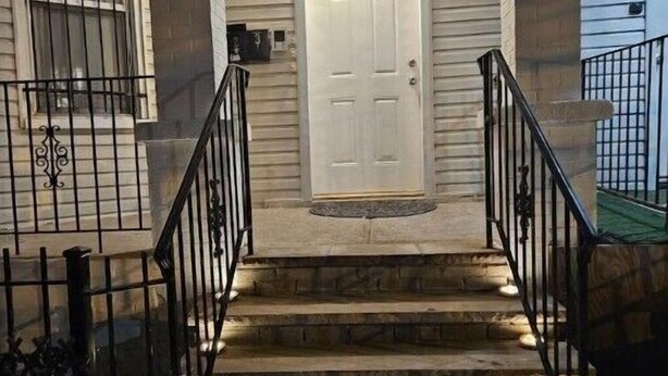 A set of stone steps leading to a white door with the number 651, flanked by black railings and a small porch area.