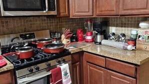 A kitchen with wooden cabinets, a microwave, a stove, and a coffee maker.