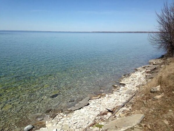 A clear view of a rocky shoreline with calm water extending to the horizon. - Le Garage🤌 (Beaverton)
