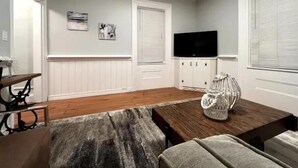 Un salon moderne avec une table basse en bois, un canapé gris et un téléviseur posé sur un meuble.