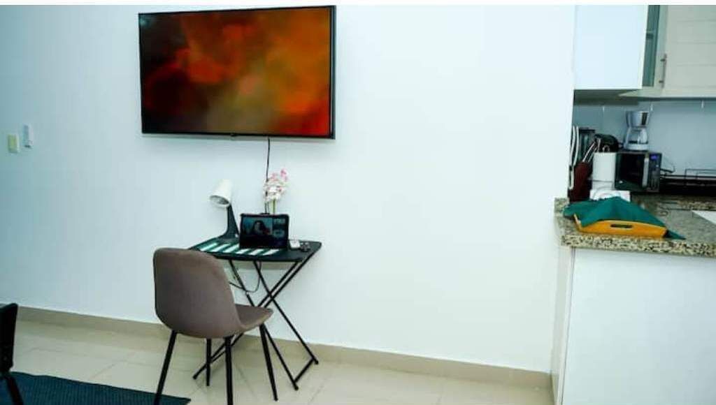 A compact living space with a dining area, a small kitchenette, and a flat-screen TV mounted on the wall.