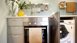 A compact kitchen with a stainless steel refrigerator, oven, and washing machine. - Monti 39 (Como)
