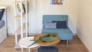 A room with a blue sofa, a white shelving unit, and a small round table with a plant. - Monti 39 (Como)