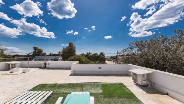 Eine Dachterrasse mit Pool, Liegestühlen und blauem Himmel.