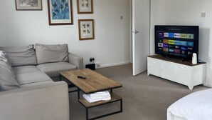 Ett modernt vardagsrum med en soffa, ett soffbord, en tv på ett tv-bord och en säng.