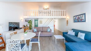 A modern living room with a TV, seating area, and a staircase leading to an upper level. - Relaxing Beach House in Alfamar by LovelyStay (Olhos de Água)