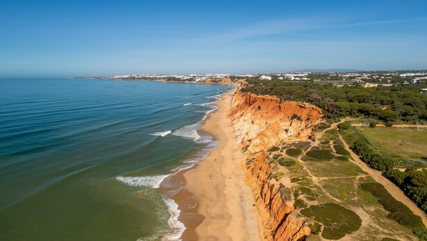 A coastal landscape with a sandy beach, cliffs, and a distant cityscape. - Relaxing Beach House in Alfamar by LovelyStay (Olhos de Água)