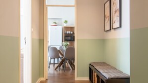 Un corridoio che conduce a una sala da pranzo con tavolo e sedie, una panca e un forno a microonde su uno scaffale.