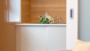 Un bagno con un mobile lavabo in legno, un lavandino bianco e un piccolo bouquet di fiori sul piano di lavoro.