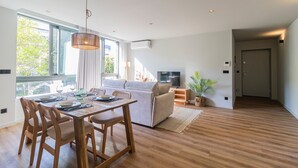 En moderne stue med spiseplads, sofa, fjernsyn og en potteplante.