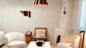 A modern living room with a white sofa, a matching armchair, a coffee table, and a hanging light fixture. - Palace Modern Residences at the Railyard - Studio (Santa Fe)
