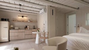 A modern bedroom with a large bed, a small dining table, and a kitchenette.