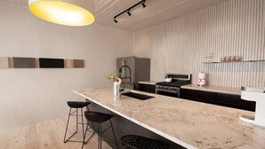 A modern kitchen with a large island, bar stools, a refrigerator, and a built-in oven.