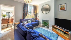 Ein modernes Wohnzimmer mit einem blauen Sofa, einem Flachbildfernseher und einem Kamin.