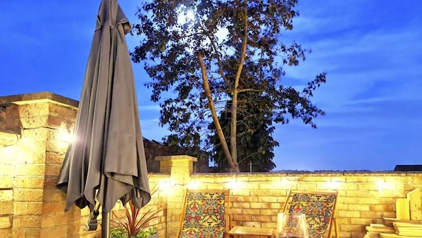 Eine Terrasse im Freien mit Tisch, Weinglas und dekorativer Wand.