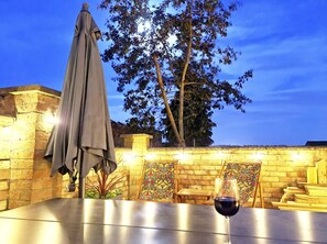 An outdoor patio with a table, a wine glass, and a decorative wall. - Luxury Lincoln Home - Sleeps 8 - Hot Tub - Pets (Lincoln)