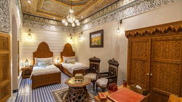 Una habitación tradicional con muebles de madera ornamentados, piso estampado y techo decorativo.