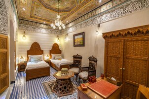 Um quarto tradicional com mobiliário de madeira ornamentado, piso estampado e teto decorativo.
