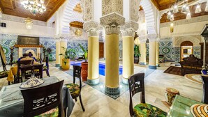 Un lobby espacioso con altos techos de madera, detalles de azulejos intrincados y una fuente central.